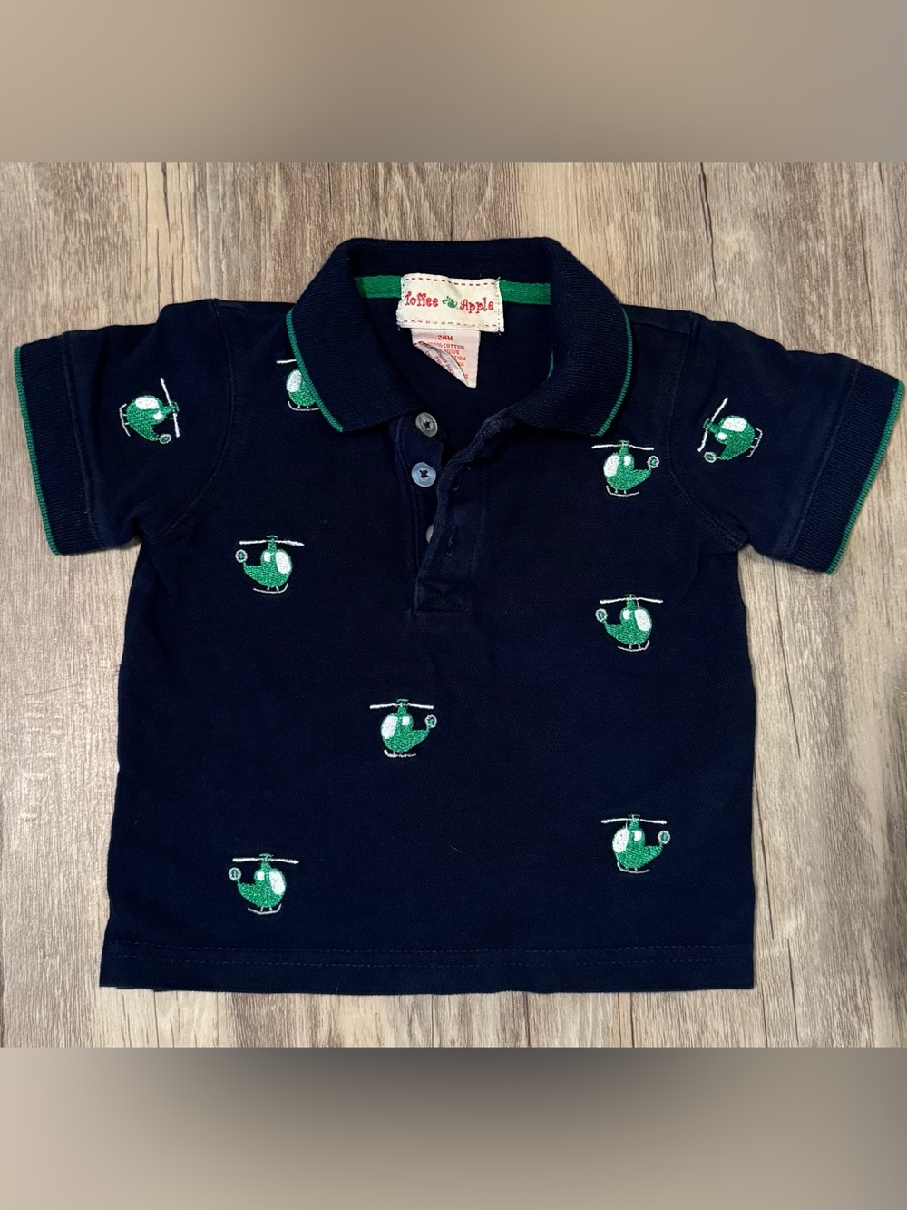 Navy blue polo shirt featuring green embroidered helicopters. Size 24.